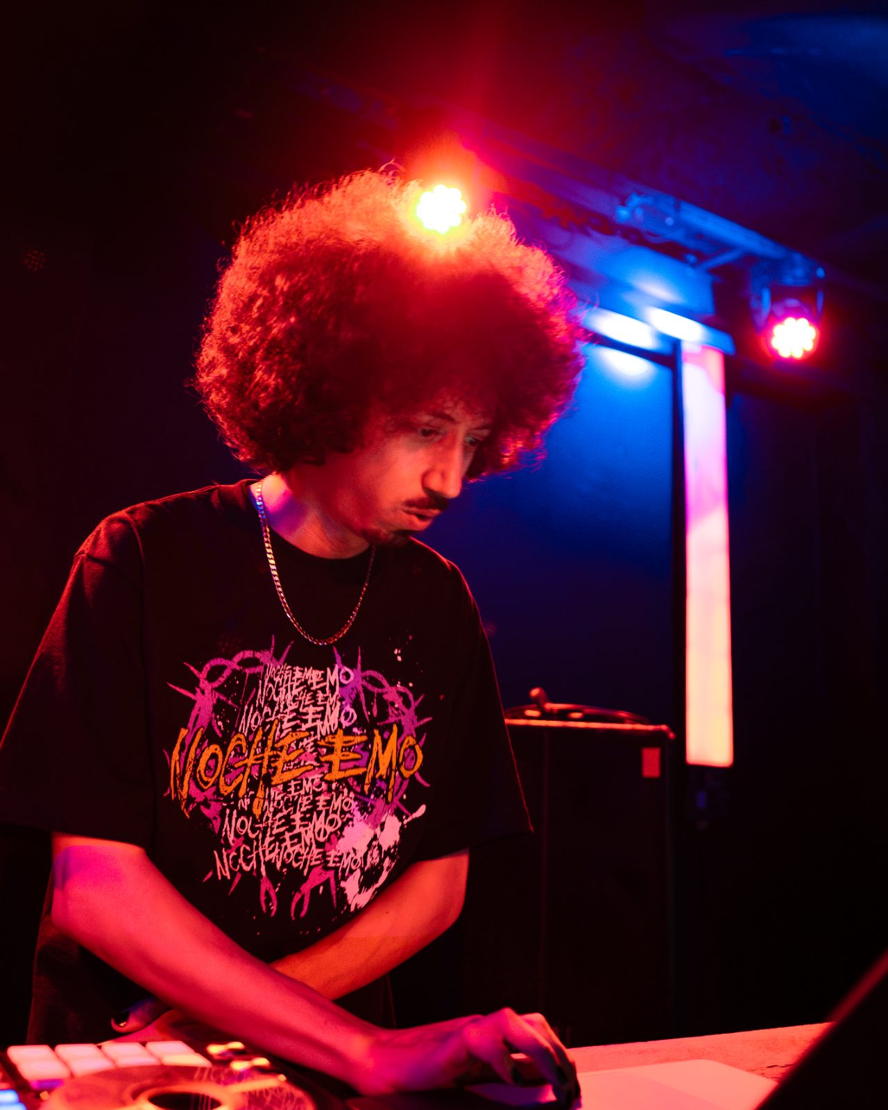 Bencore concentrating on a live mix under red and blue lights